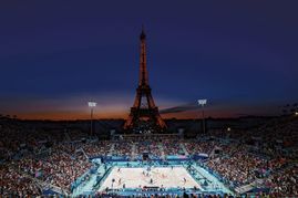Ein unglaublich stimmungsvolles Bild: Der Beachvolleyball-Wettbewerb bei den olympischen Spielen 2024 im Abendlicht von Paris vor dem Eiffelturm.